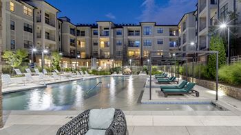 an apartment swimming pool with lounge chairs at night at The Hendrix, Atlanta, GA